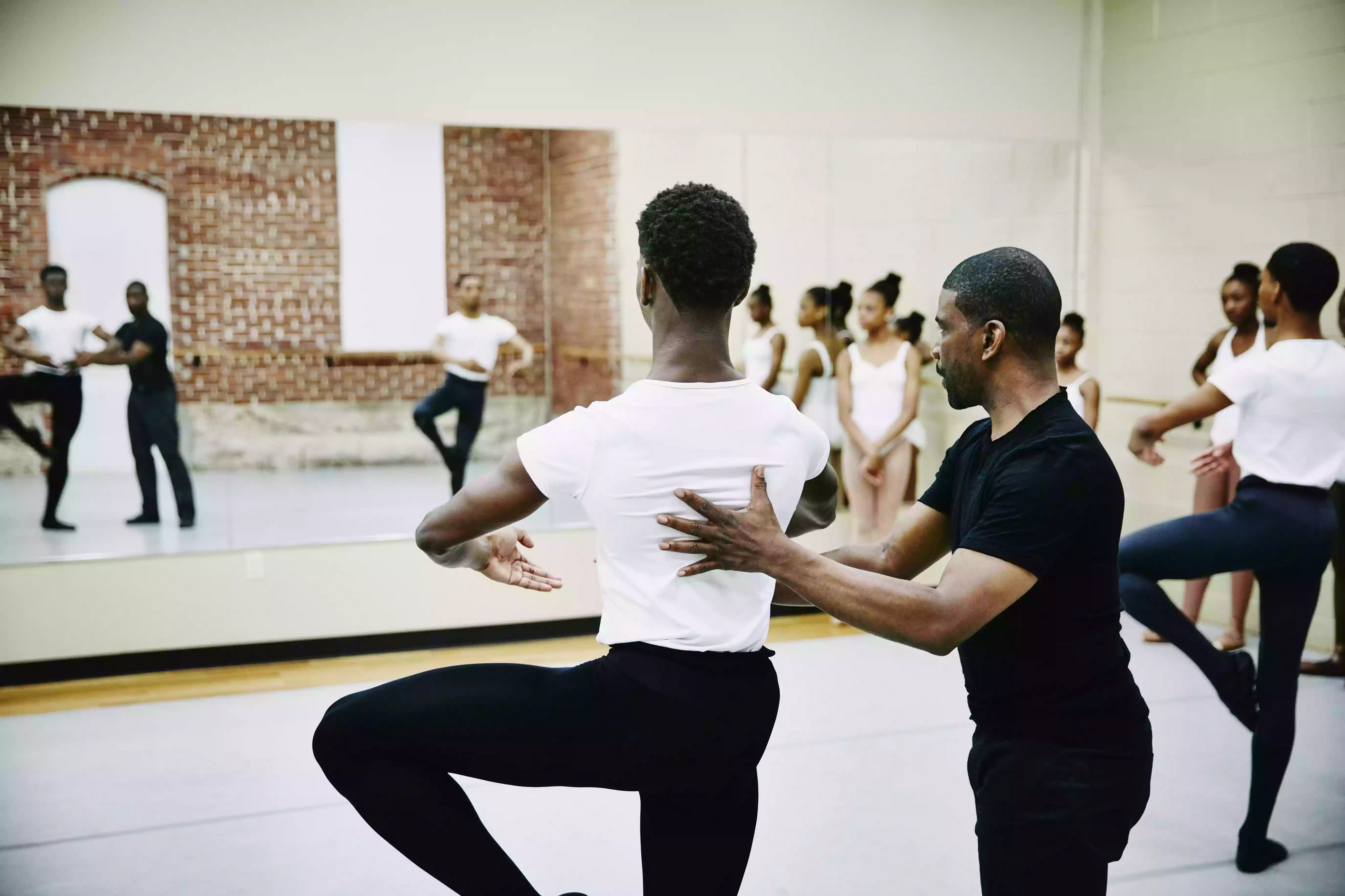 Ballet instructor adjusting students form